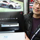 A man in a black jacket and glasses holds up a PlayStation 3.